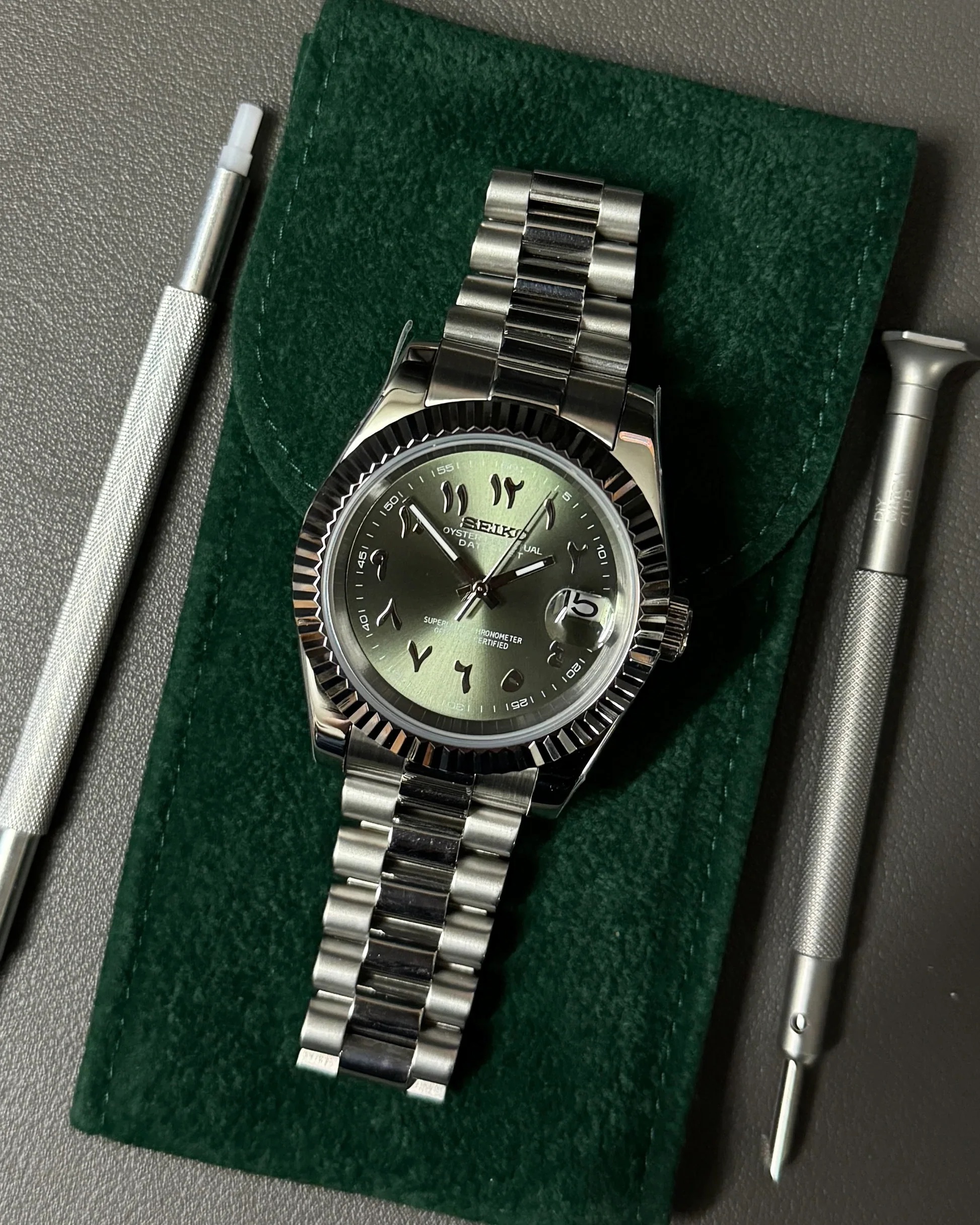Arabic numeral green dial on watchmaker's roll with tools